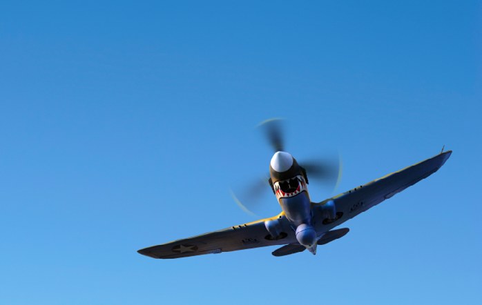 A propeller aircraft with intentionally motion-blurred propeller against a blue sky