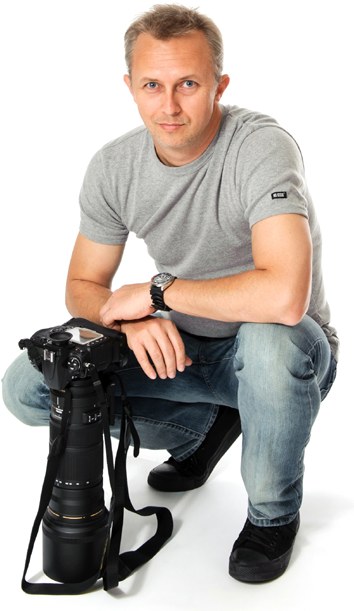 Photographer Dallas Dahms crouching with a camera and long telephoto lens