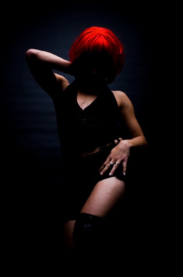 A dramatic low-key studio portrait of a red-haired model