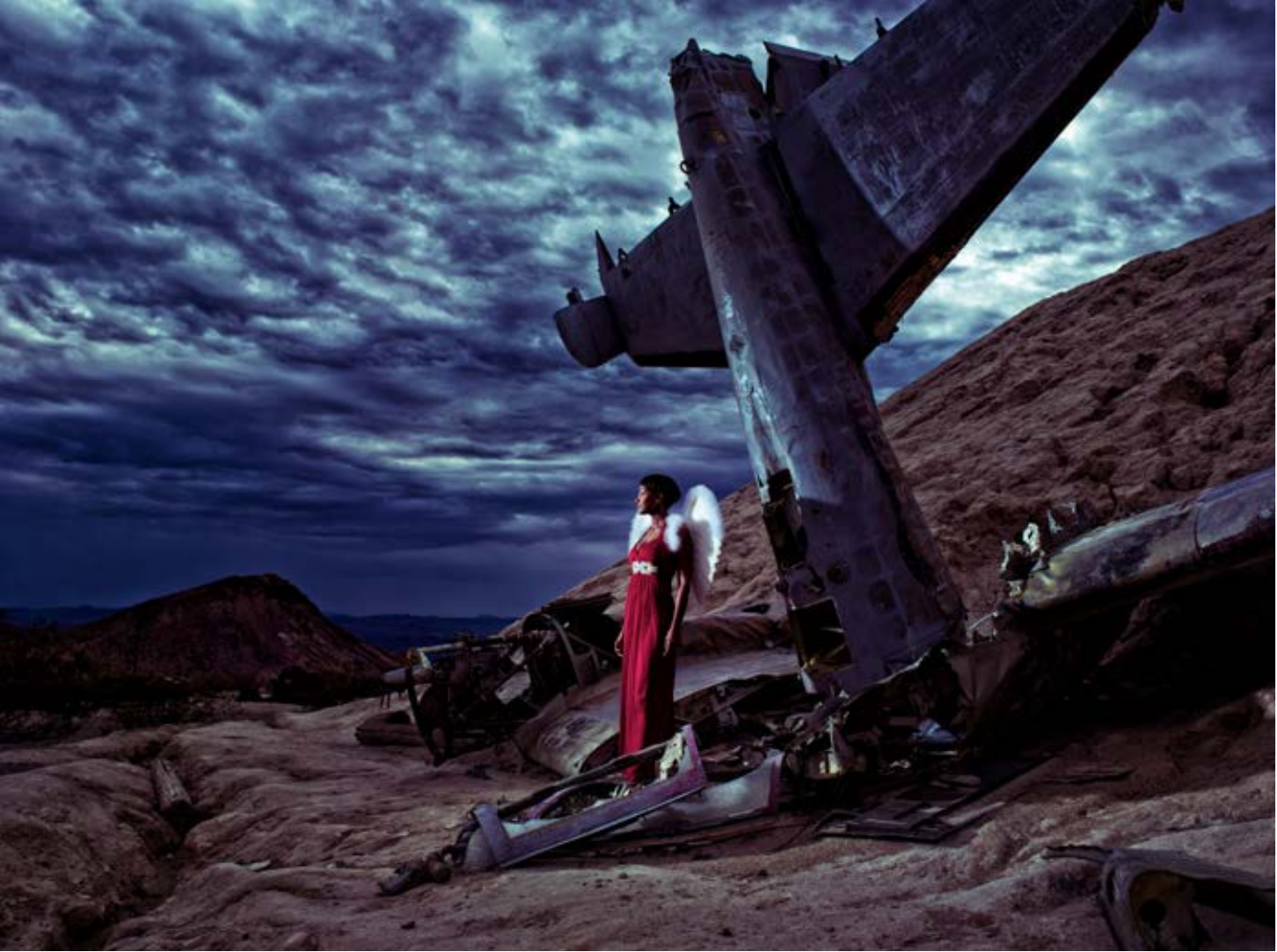 Conceptual fashion photograph by Frank Doorhof, a model beside a wrecked aircraft at dusk