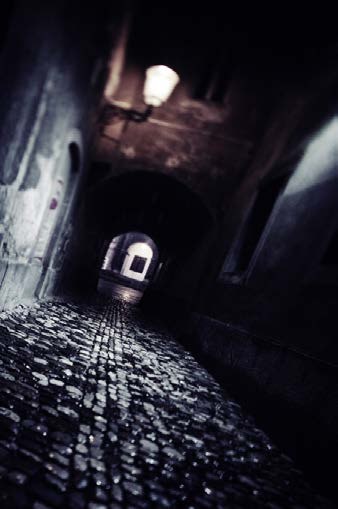 A dark, off-kilter cobblestone street and archway used to create visual tension