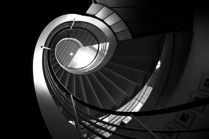 A dramatic black and white photograph of a spiral staircase
