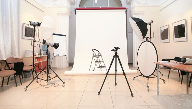 A photography studio set up with backdrop, strobes, and a round reflector