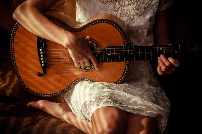 A warmly lit studio portrait of a woman holding an acoustic guitar